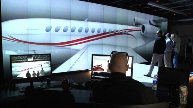 Large video wall display shows falcon jet - 2 men observe while another controls the screen