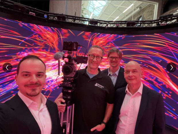 Smiling Mechdyne, Bristol, and Beeston media teammates standing in a large scale visualization space
